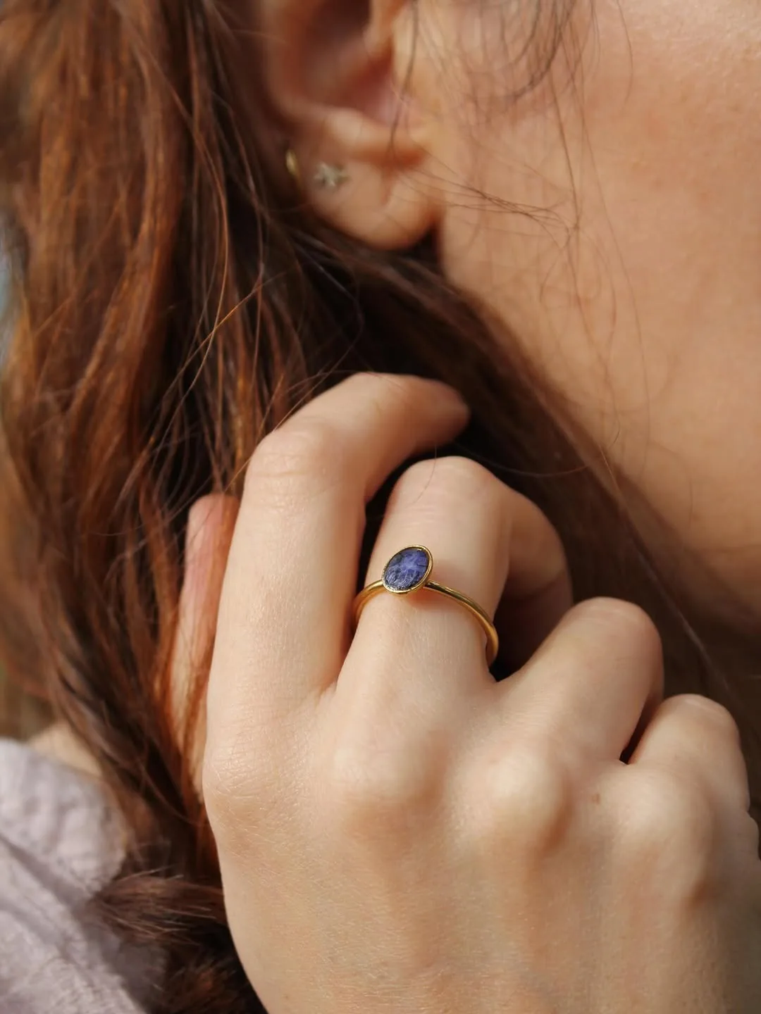 Anillo dorado con piedra azul de resina en una mano