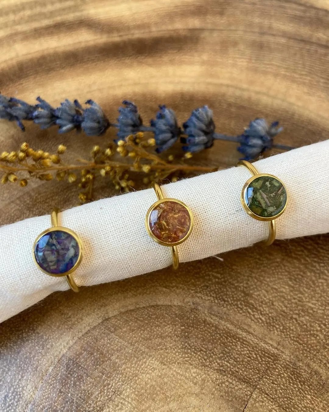 Tres anillos finos con flores en resina sobre un soporte